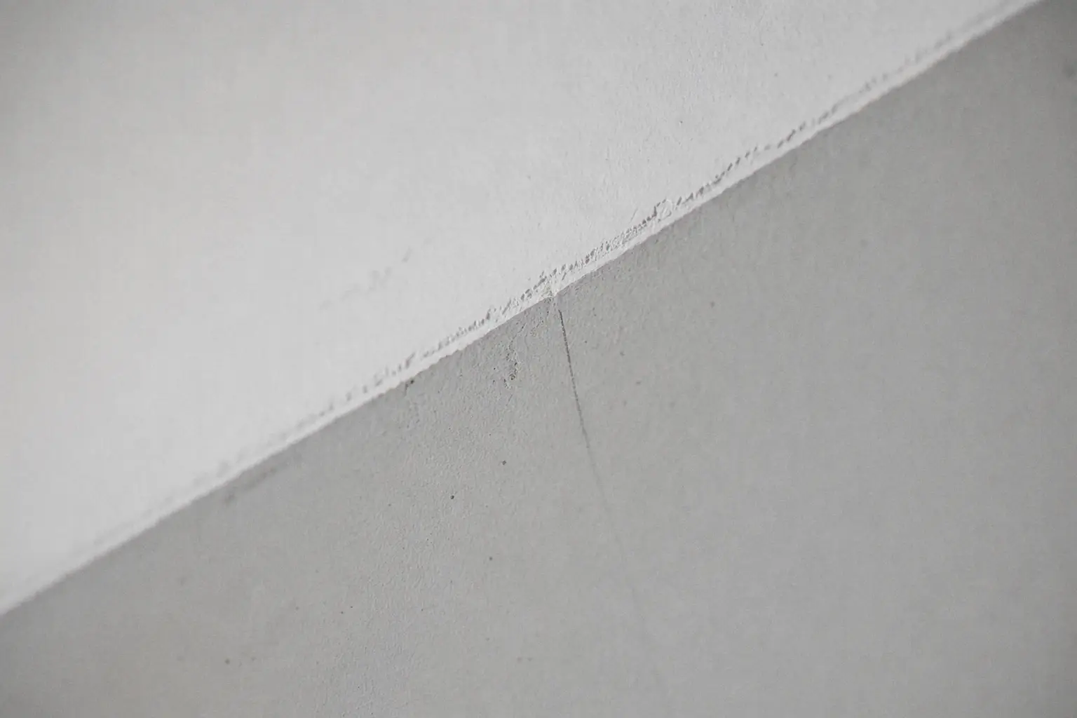 Crisp edge between a freshly painted pure-white ceiling and a silk-grey wall
