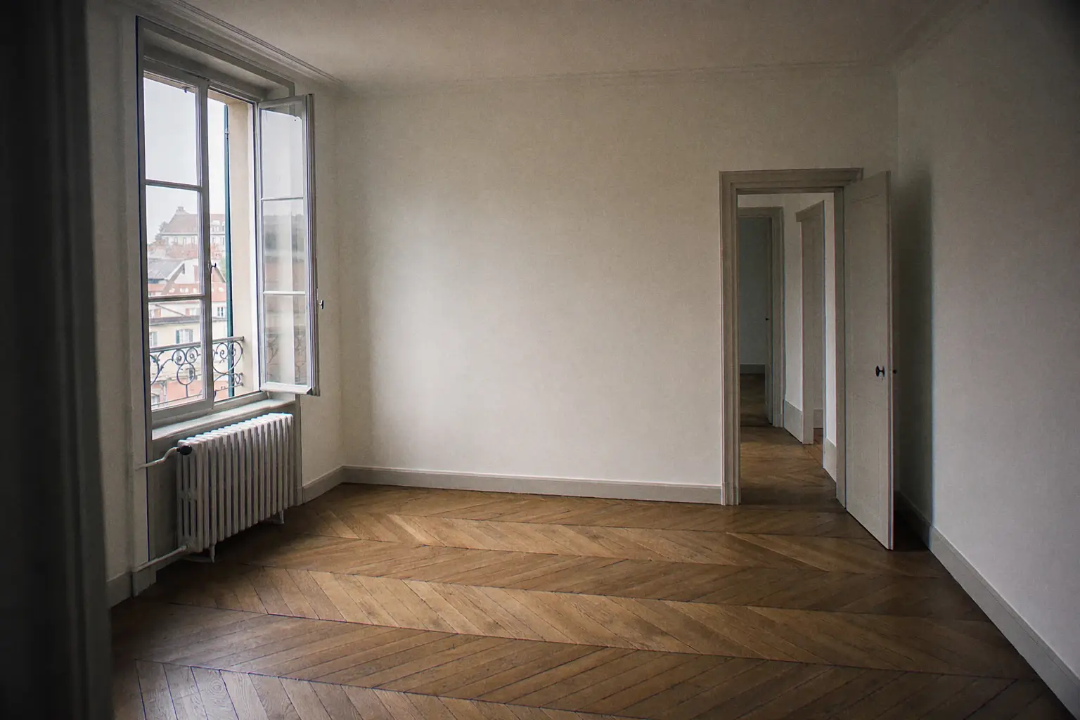Empty living room of a Geneva apartment refurbished between two tenancies, off-white walls and oak parquet