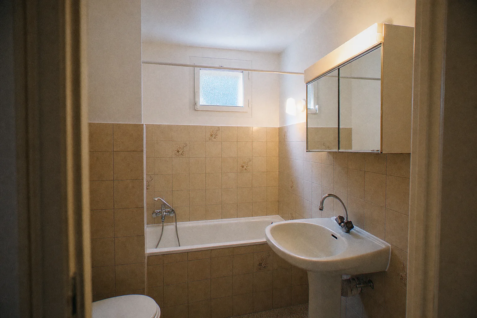Rental apartment bathroom restored after water damage: ceiling and upper walls repainted, original tiling preserved