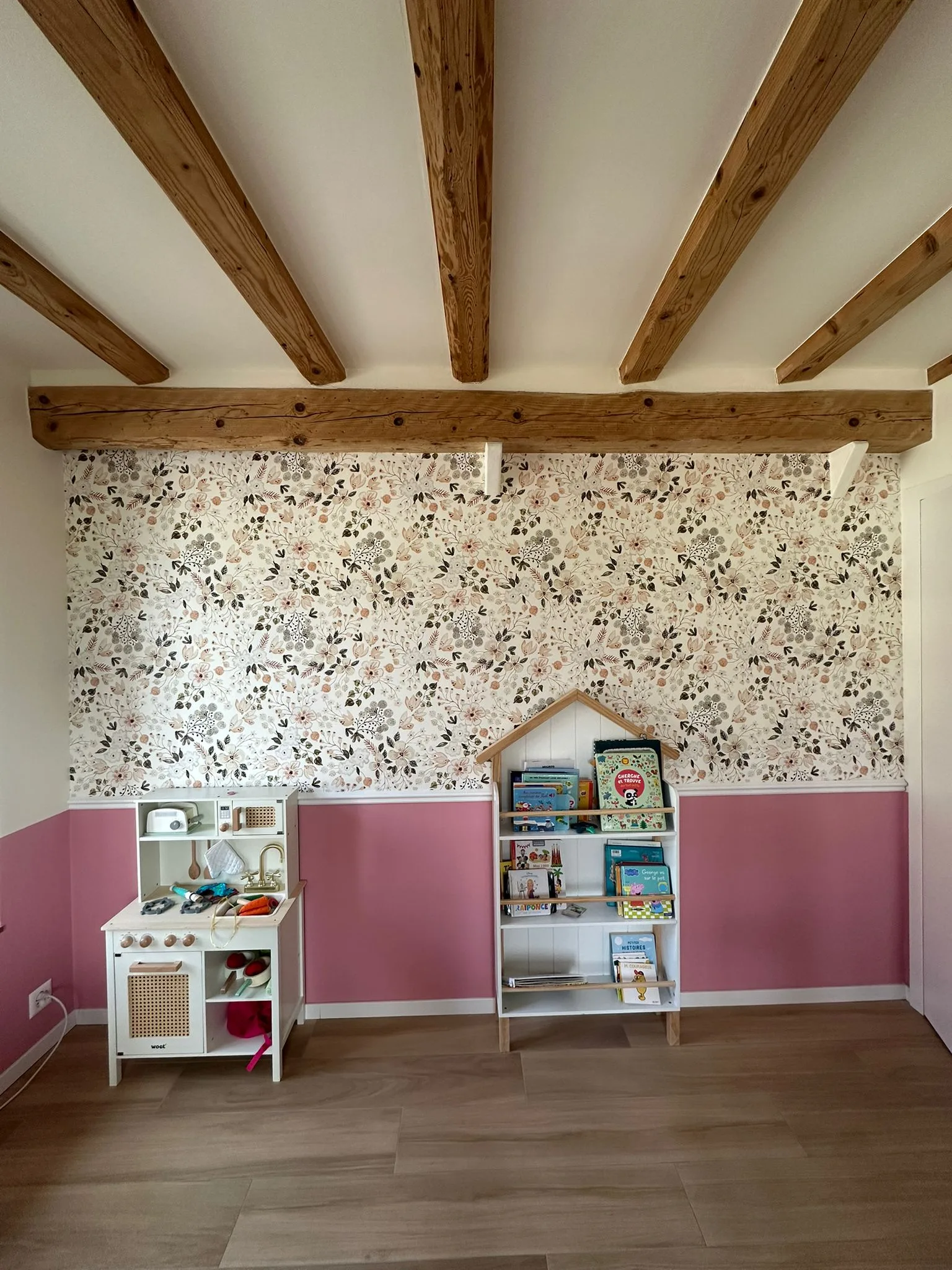 Child's bedroom in Geneva: floral wallpaper on the upper wall, a pink-painted dado on the lower wall, separated by a white MDF dado rail (moulding), beneath exposed beams.