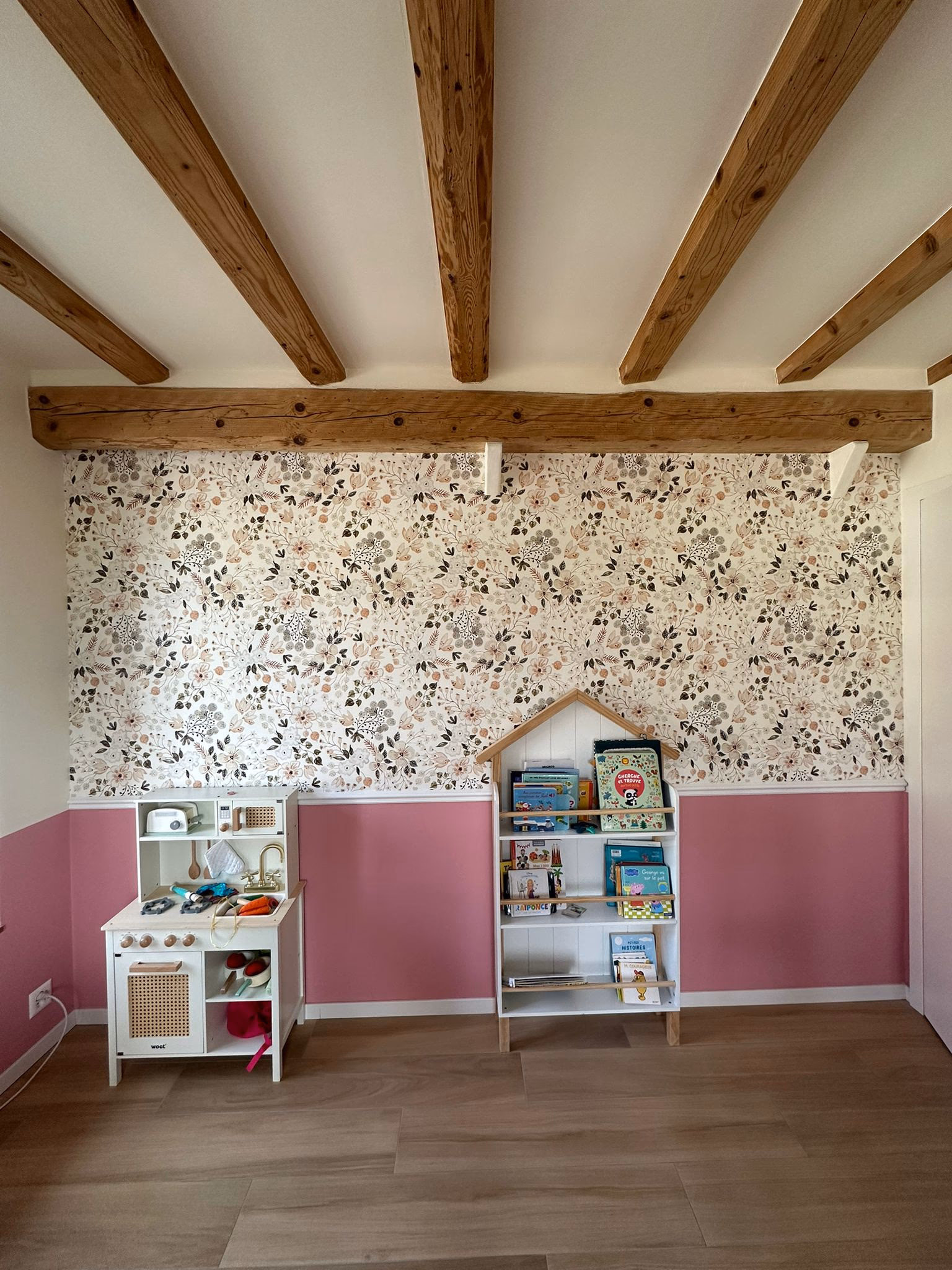 Child's bedroom in Geneva: floral wallpaper on the upper wall, a pink-painted dado on the lower wall, separated by a white MDF dado rail (moulding), beneath exposed beams.