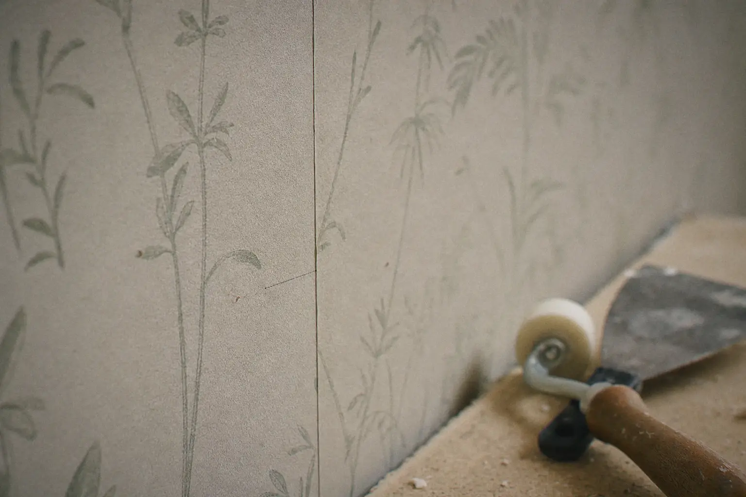 Near-invisible seam between two strips of non-woven wallpaper with a botanical pattern